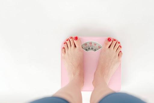 A female girl with red nailpolish standing in a weighing scale